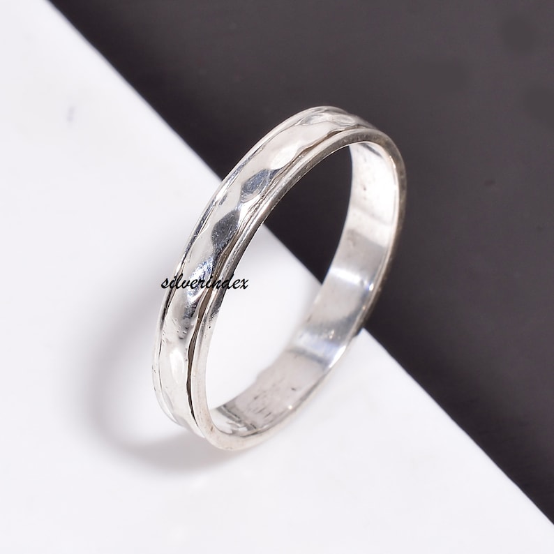 May include: A silver hammered band ring. The ring is simple and elegant, with a smooth, polished finish.