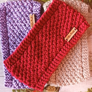 May include: Three knitted headbands in purple, red, and beige with a wooden tag that says "Celtic Pearls" on each.