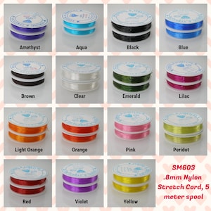 May include: A variety of colors of 0.8mm nylon stretch cord, each color is wound on a spool. The colors include amethyst, aqua, black, blue, brown, clear, emerald, lilac, light orange, orange, pink, peridot, red, violet, and yellow. The text on the spool reads "SM603 .8mm Nylon Stretch Cord, 5 meter spool".