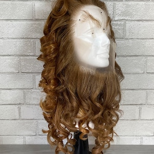 Puede incluir: Una peluca rizada marrón con un lazo rojo en una cabeza de maniquí. La peluca está peinada en un recogido vintage con rizos sueltos.
