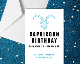 May include: A white card with a blue Capricorn zodiac symbol and the text "Capricorn Birthday" in black. The date range "December 22 - January 20" is printed below the title. The text "Capricorn - shoplifts from Poundland." is printed at the bottom of the card.