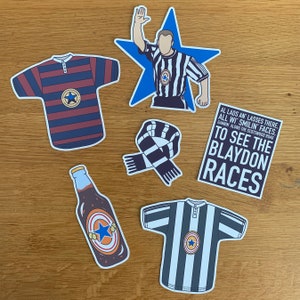 May include: A set of five stickers featuring a black and white striped football shirt, a black and white striped scarf, a blue star with a referee in a black and white striped shirt, a brown bottle with a white star, and a black and white striped football shirt with the text "AL LADS AN LASSES THERE. ALL WI SMILIN' FACES. GANNIN' ALONG THE SCOTSWOOD ROAD TO SEE THE BLAYDON RACES".