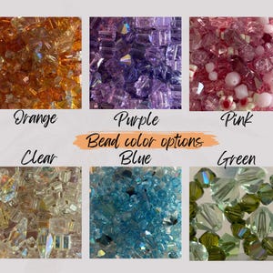 May include: A selection of colourful glass beads in various colours, including orange, purple, pink, clear, blue, and green. The beads are arranged in six separate groups, each labelled with its corresponding colour. The text "Bead colour options" is displayed in the centre of the image.