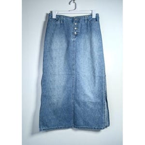 May include: A long denim skirt with a button closure and a slit on each side. The skirt is a light blue wash and has a relaxed fit.