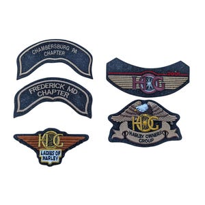 May include: Collection of embroidered patches featuring the Harley Owners Group (HOG) logo and text. Patches include "Chambersburg PA Chapter," "Frederick MD Chapter," and "Ladies of Harley." The patches are in various shapes and colors.