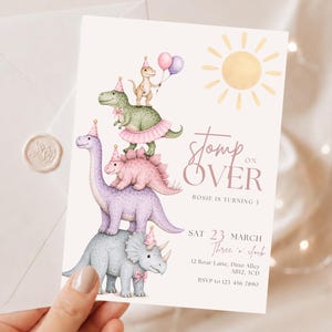 Puede incluir: Una tarjeta de invitación de cumpleaños rectangular blanca con una pila de cuatro dinosaurios ilustrados con gorros de fiesta, un sol amarillo y el texto "stomp on OVER ROSIE IS TURNING 1 SAT 23 MARCH Three o'clock 12 Rose Lane, Dino Alley AB12 3CD RSVP to 123-456-7890".