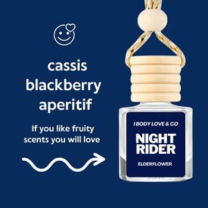 May include: A small, clear glass bottle with a wooden cap and a hanging string. The label reads "NIGHT RIDER ELDERFLOWER" and "I BODY LOVE & CO". Text on the left says "cassis blackberry aperitif" and "If you like fruity scents you will love".