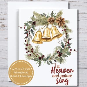 May include: A Christmas card with a watercolor design. The card features a wreath of greenery, berries, and pinecones, with three golden bells hanging in the center. The text "Let Heaven and nature sing" is written in red script. The card measures 4.25 x 5.5 inches.