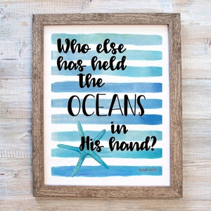 May include: A framed print with a watercolor background of blue and white stripes. The print features the text "Who else has held the oceans in His hand?" with a starfish in the center. The text "Isaiah 40:12" is at the bottom of the print.