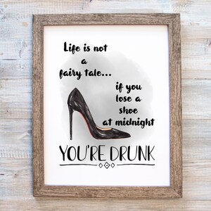 May include: A black and white printable art print with a quote that reads "Life is not a fairy tale... if you lose a shoe at midnight YOU'RE DRUNK". The quote is accompanied by a drawing of a black high heel shoe.