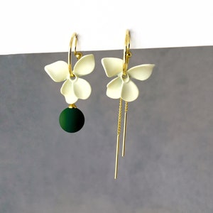 Mismatched white flower dangle clip on earrings with matte green ball and gold chains, invisible clip on earrings