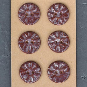 May include: A set of three ceramic mugs with a speckled, matte finish. The mugs are in shades of cream, light gray, and dark gray. Each mug has a simple, modern design and a rounded handle.