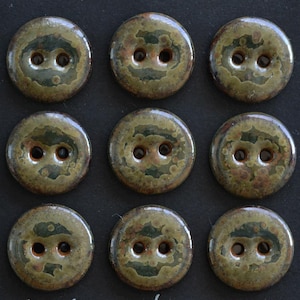 May include: A set of nine round ceramic buttons arranged in a three-by-three grid. Each button features a two-hole design and a mottled glaze finish in shades of olive green, dark brown, and tan with a glossy, reflective surface texture.