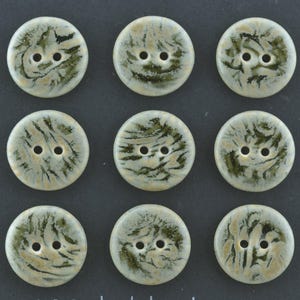 Puede incluir: Nueve botones redondos con dos agujeros cada uno. Los botones tienen una base color crema con un patrón veteado en verde oliva y beige. Los botones están dispuestos en una cuadrícula de tres por tres sobre un fondo oscuro.