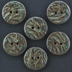 May include: Six ceramic buttons with a round shape and two holes each. The buttons have a teal and brown swirl pattern. These decorative buttons are suitable for sewing and craft projects.