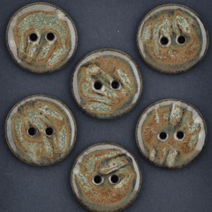 May include: Six ceramic buttons with two holes each. The buttons are round with a mottled design in shades of brown, green, and cream. The buttons have a glossy finish and a raised edge.