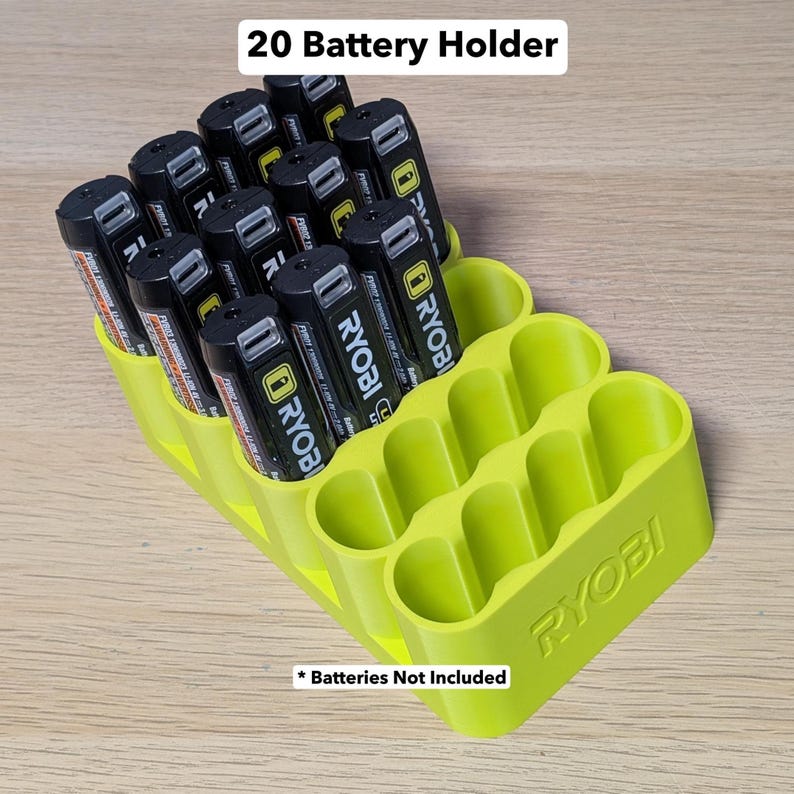 K&ouml;nnte beinhalten: Ein limettengr&uuml;ner 20-Batterie-Halter, gef&uuml;llt mit schwarzen und gelben Batterien. Der Halter hat den Markennamen "RYOBI" auf der Seite eingepr&auml;gt. Der Text "20 Battery Holder" steht oben und "Batteries Not Included" unten.