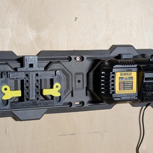 May include: A black and gray wall-mounted power tool organizer with a black and yellow DeWalt battery charger and a black and yellow tool holder. The organizer is mounted on a light wood surface.