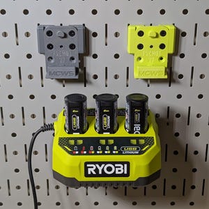 May include: A lime green and black Ryobi USB lithium battery charger with three black batteries. Two gray and yellow battery holders are mounted above the charger on a pegboard. The charger has indicator lights and the Ryobi logo.