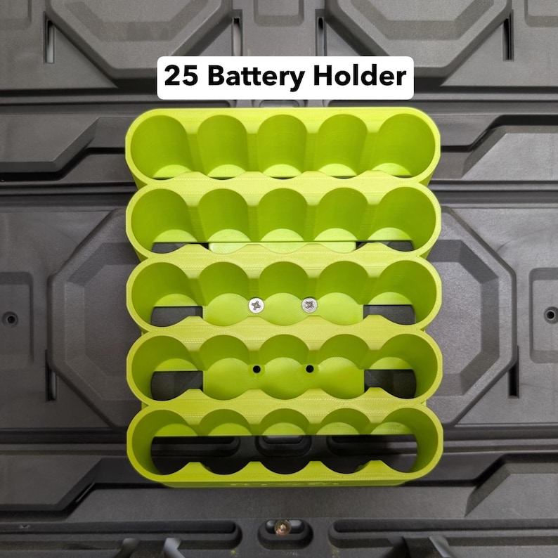 K&ouml;nnte beinhalten: Ein limettengr&uuml;ner 25-Batteriehalter mit f&uuml;nf Reihen zu je f&uuml;nf kreisf&ouml;rmigen Schlitzen. Der Halter ist auf einer dunkelgrauen, strukturierten Oberfl&auml;che montiert. Der Text "25 Battery Holder" wird oben in Wei&szlig; angezeigt.