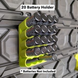 K&ouml;nnte beinhalten: Ein limettengr&uuml;ner 20-Batterie-Halter an einer grauen Wand montiert. Der Halter ist f&uuml;r die Aufbewahrung von 20 AA-Batterien konzipiert. Die Batterien sind schwarz und silberfarben. Der Text auf dem Bild lautet "20 Battery Holder" und "Batteries Not Included".