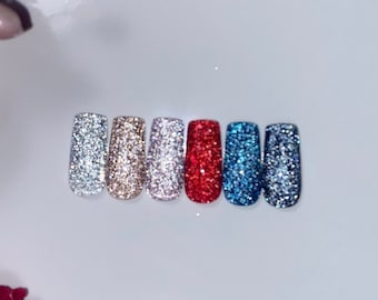 May include: Set of six glitter press-on nails in various colors, including silver, gold, pink, red, blue, and light blue.