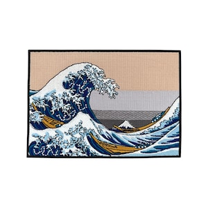 May include: An embroidered patch featuring a blue and white wave with a mountain in the background. The wave is breaking and there are three boats in the foreground. The patch is surrounded by a black border.