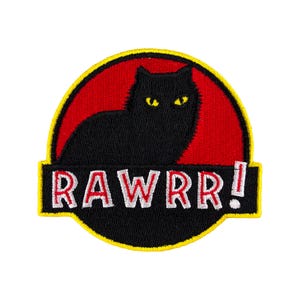 Op de afbeelding: Zwarte kat silhouet in een rode cirkel met een gele omtrek, die lijkt op een dinosaurus, met de tekst "RAWRR!" eronder.