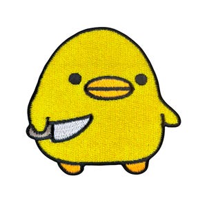 May include: A yellow embroidered patch of a cartoon chick holding a knife. The chick has black eyes and a black beak.