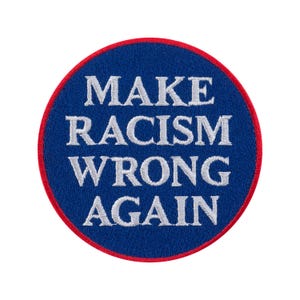 Könnte beinhalten: Ein runder, gestickter Aufnäher mit blauem Hintergrund und rotem Rand. Der Aufnäher zeigt den weißen Text "MAKE RACISM WRONG AGAIN" in einer fetten, serifenlosen Schrift. Der Aufnäher ist zum Aufnähen oder Aufbügeln auf Kleidung oder Accessoires gedacht.