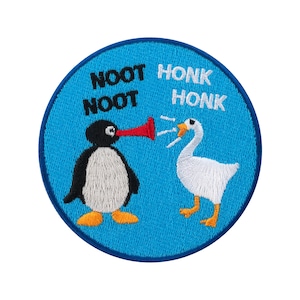 May include: A round, blue embroidered patch featuring a penguin and a goose. The penguin has a red megaphone, and the goose is honking. Text on the patch reads "NOOT NOOT" and "HONK HONK".