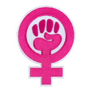 May include: A pink embroidered patch featuring a white fist inside a circle, with the symbol for female below. The patch has a white border and is on a white background. The design is a symbol of female empowerment.
