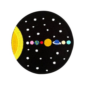 Peut inclure: Un patch en feutre noir avec une image brodée du système solaire. Le soleil est jaune, les planètes sont de différentes couleurs et il y a des étoiles blanches en arrière-plan.