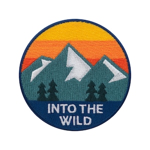 Könnte beinhalten: Runder, gestickter Aufnäher mit einer Berglandschaft. Das Design zeigt eine blaue Bergkette mit weißen Gipfeln, grüne Bäume und einen Sonnenuntergang in Orange- und Gelbtönen. Der Text "INTO THE WILD" ist weiß auf blauem Grund.