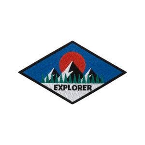 May include: Embroidered patch in a diamond shape, depicting a mountain range, a red sun, and green trees against a blue sky. The word "EXPLORER" is embroidered in white. The patch has a black border.