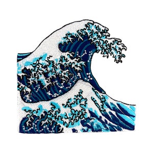 Op de afbeelding: Gestikte patch met een blauw en wit golfontwerp, doet denken aan de Grote Golf voor Kanagawa, een beroemde Japanse houtsnede.