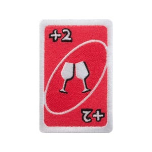 Puede incluir: Un parche rojo bordado que se asemeja a una carta +2 Uno. La tarjeta presenta dos copas de vino brindando dentro de un óvalo, con "+2" en la parte superior e inferior. El parche tiene un borde blanco.
