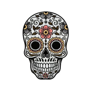 Puede incluir: Una calavera de azúcar blanca con ojos negros y una flor rosa en la frente. La calavera está decorada con intrincados patrones florales en negro, amarillo y rosa.