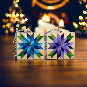 May include: Two wooden ornaments with a snowflake design. One ornament is blue and green, the other is purple and green.