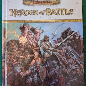 May include: A Dungeons & Dragons book cover featuring the title "Heroes of Battle" in gold lettering. The cover art depicts a diverse group of fantasy characters in a battle scene, including a warrior, a mage, a rogue, and a dragon.