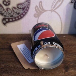 May include: Black and red soda can candle with a white wax interior and a brown twine bow. The can has the text "Pepsi" and "Be Sold As Multipack Only" printed on it.