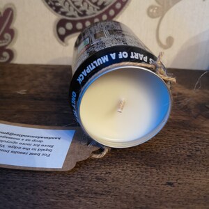 May include: A white candle in a repurposed aluminum can with a black label that reads "S PART OF A MULTIPACK ONLY TO". A brown paper tag with instructions for using the candle is attached to the can with twine.