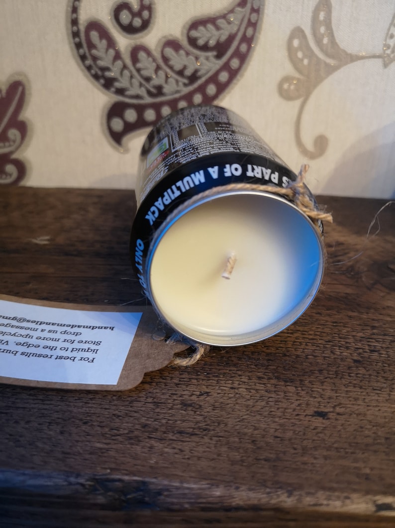 May include: A white candle in a repurposed aluminum can with a black label that reads "S PART OF A MULTIPACK ONLY TO". A brown paper tag with instructions for using the candle is attached to the can with twine.