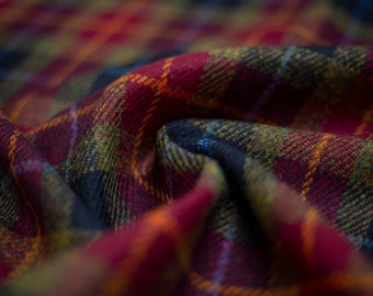 May include: Close-up of a red, orange, green, and blue plaid fabric. The fabric is folded and textured.