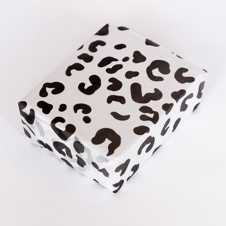 May include: White gift wrapping paper with a black leopard print pattern.