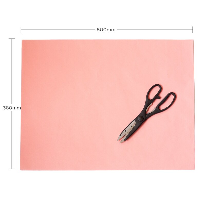 May include: A pink sheet of paper measuring 380mm by 500mm with a pair of black kitchen shears on top.