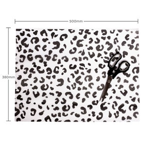 May include: Black and white leopard print wrapping paper with a pair of scissors on top. The paper measures 380mm by 500mm.
