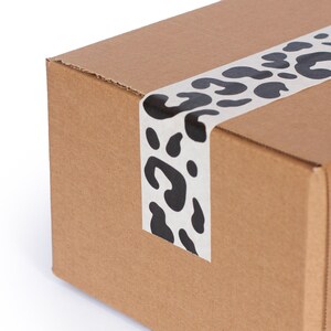 May include: A brown cardboard box with a white and black leopard print tape across the top.