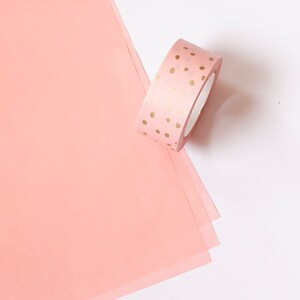 May include: A roll of pink washi tape with gold polka dots.