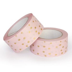 K&ouml;nnte beinhalten: Zwei Rollen rosa Washi-Tape mit goldenen Punkten.
